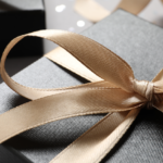 Beautiful gift box with bow on grey background, closeup view