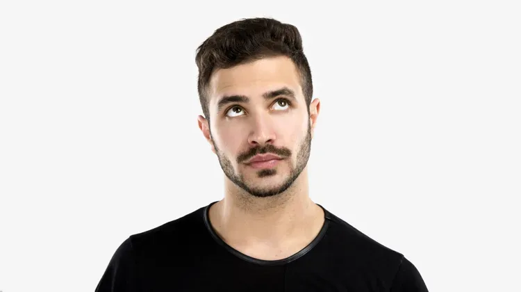 Man tilts his head slightly to the left with his eyes looking upward in contemplation.